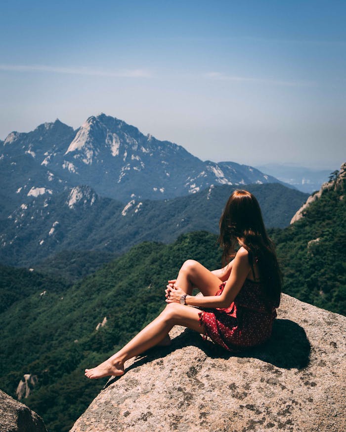 services-02 A woman sitting on a rock, admiring scenic mountain views during summer.